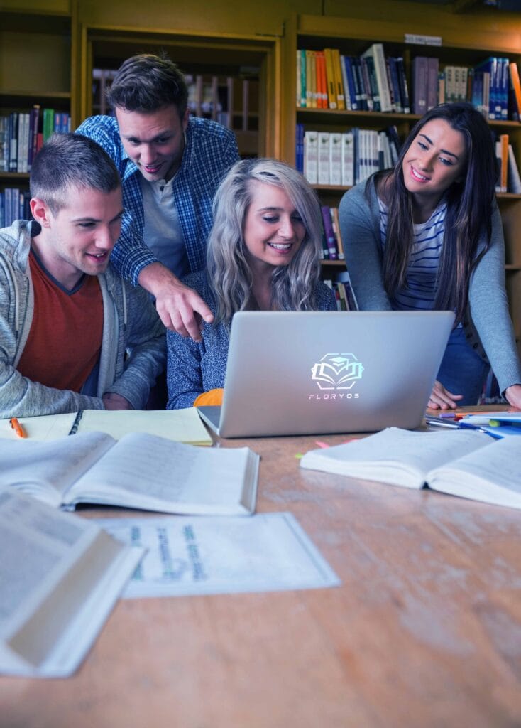Group of four happy students using laptop at desk in the college library